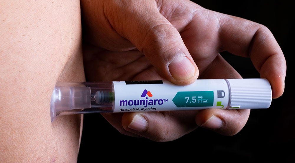 Mão aplicando o medicamento Mounjaro com orientação dos especialistas da Lybe Clinic